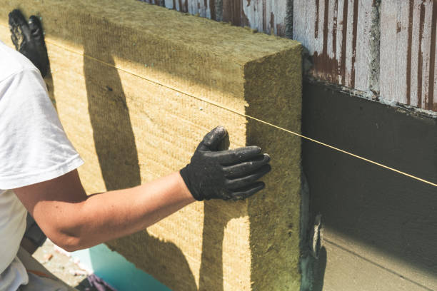 Worker installing rock wool panels on facade wall Утеплення фасаду мінеральною ватою